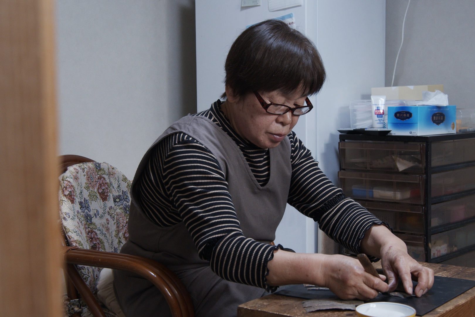 自宅の作業机で樺細工に文様を施す職人